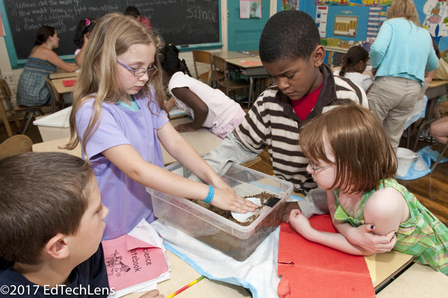 A third-grade student group works on the problem of soil erosion and how it could be minimized or prevented. Student groups created mini-ecosystems after collecting materials including plastic tubs, soil, tools for shaping soil, plastic wrap to cover the tubs, and various containers to simulate precipitation. A third-grade student group in works on the problem of soil erosion and how it could be minimized or prevented.