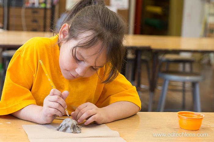 A kindergartner at a school with a Rainforest Journey subscription uses a pencil to make a pattern on the shell of her turtle in art class. The art lesson included scientific and art concepts, and students also learned how to use clay and clay tools to make their turtles.