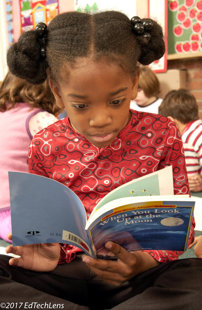 Grade 1 student reading nonfiction science book at class reading time